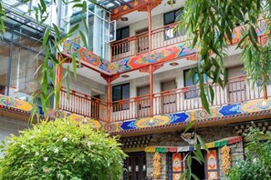A multi-level building with balconies adorned with colorful patterns, surrounded by greenery. - Ganbao Tibetan Village Jingji Chamayi Inn Homestay (Li County)
