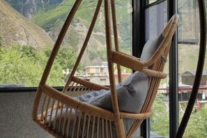 A wicker chair with cushions, a window, and a view of green hills. - Ganbao Tibetan Village Jingji Chamayi Inn Homestay (Li County)
