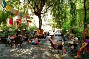 An outdoor seating area with tables and chairs, surrounded by trees and greenery. - Ganbao Tibetan Village Jingji Chamayi Inn Homestay (Li County)