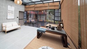 Un intérieur moderne avec un plafond en verre, un canapé blanc, une table en bois agrémentée d’objets décoratifs et une vue dégagée grâce à de grandes fenêtres.