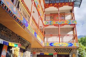 A multi-story building with balconies adorned with colorful patterns, a stone facade, and a traditional architectural style. - Ganbao Tibetan Village Jingji Chamayi Inn Homestay (Li County)