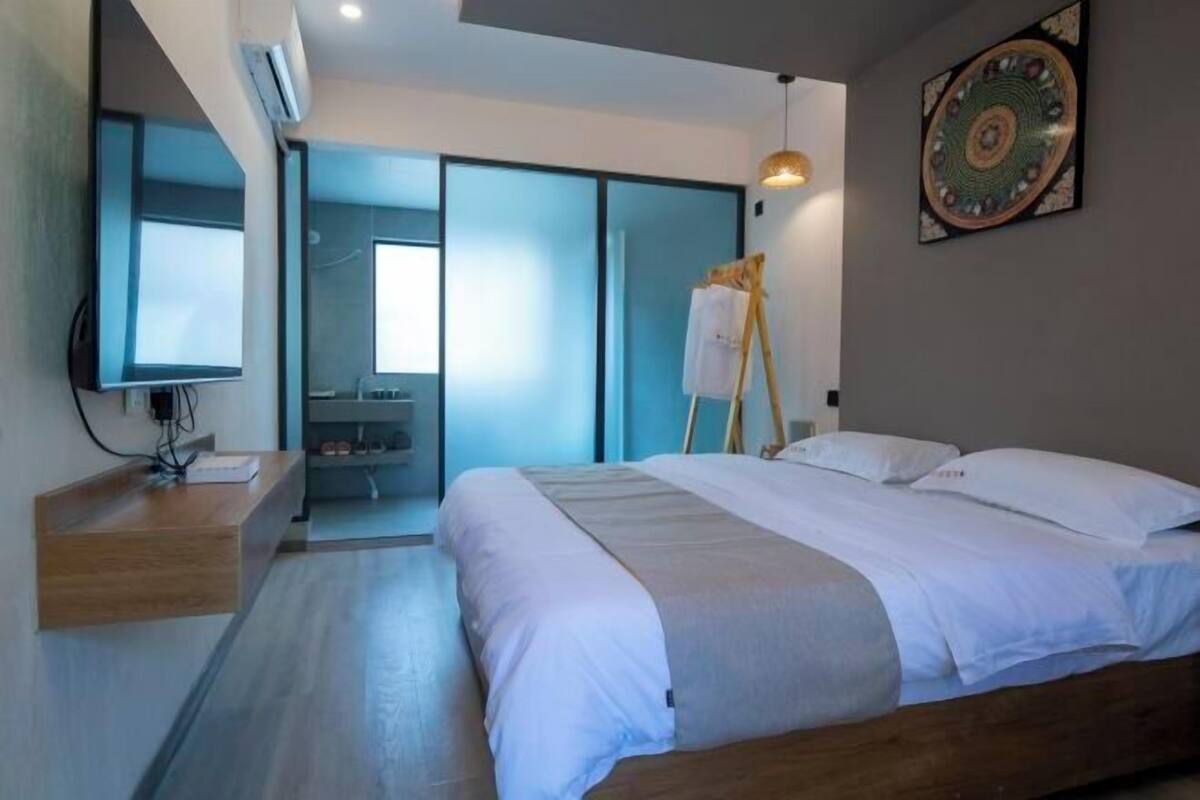 Un hotel moderno con cama, escritorio, espejo y un cuadro en la pared.