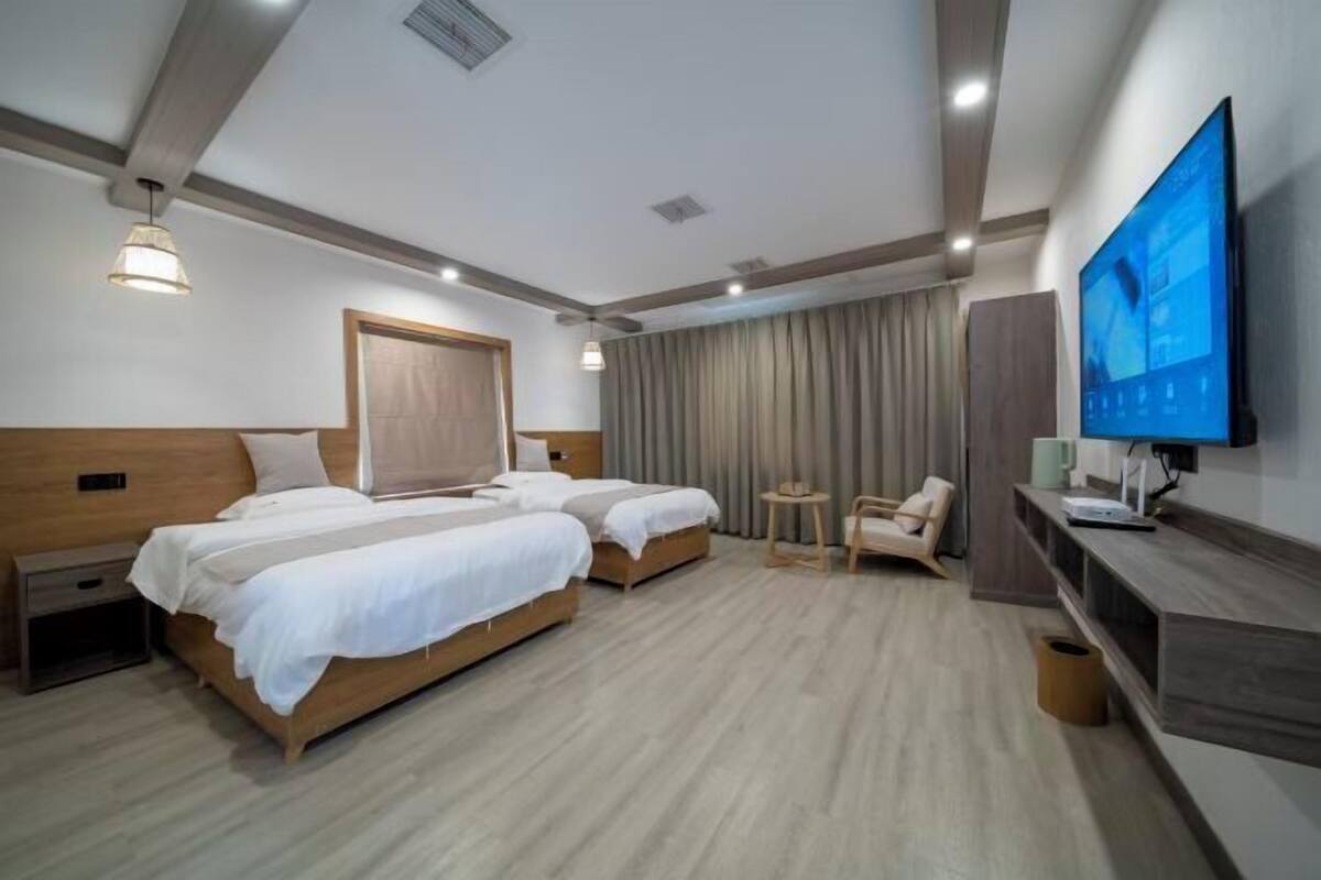 Una habitación de hotel con dos camas, televisión, escritorio y una silla.