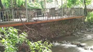 A stone bridge over a flowing river with a railing and benches.