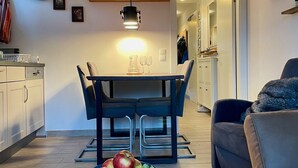 A modern kitchen with a dining table, chairs, and a bowl of fruit. There is a sofa and a coffee table in the living area. - Residence Alpin TOP 6 - Kaprun incl SUMMER CARD (Kaprun)