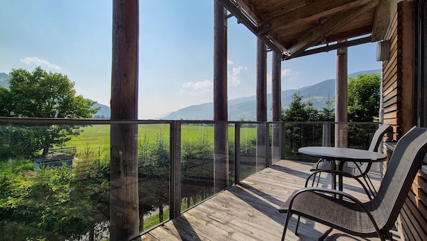 A wooden deck with a glass railing overlooking a green landscape and mountains. - Residence Alpin TOP 6 - Kaprun incl SUMMER CARD (Kaprun)
