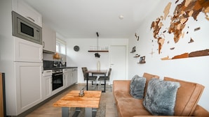A modern kitchen with white cabinets, a wooden dining table, and a leather sofa with fur throw pillows. - Residence Alpin TOP 6 - Kaprun incl SUMMER CARD (Kaprun)