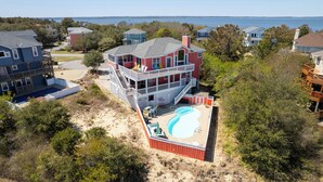 A multi-story house with a large backyard and a swimming pool. - Spacious Pet Friendly 6-bedroom all season retreat in Corolla w/ pool and sauna (Corolla)