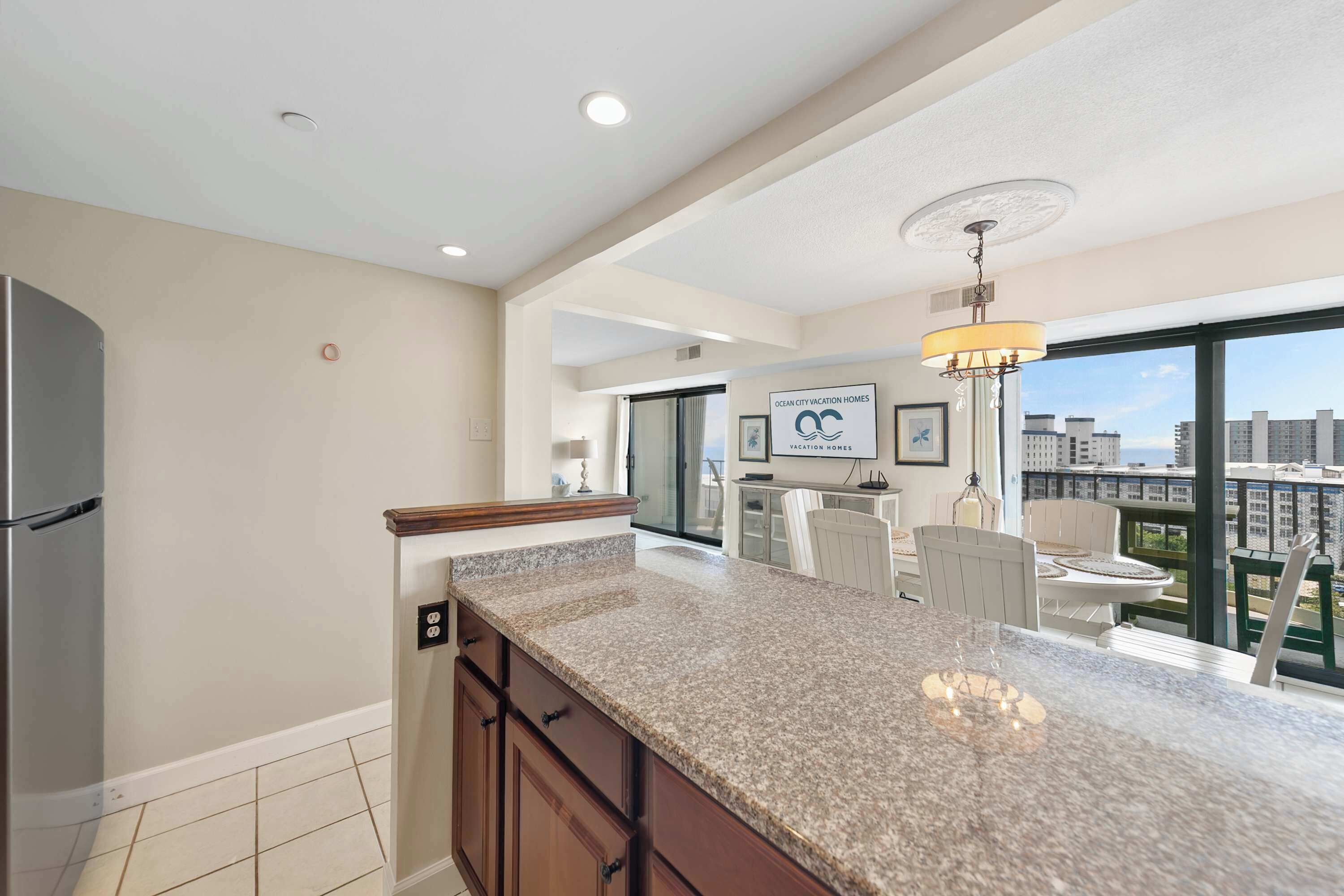 A modern kitchen with granite countertops, a built-in refrigerator, and a dining area with a view of the city.