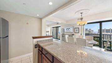 A modern kitchen with granite countertops, a built-in refrigerator, and a dining area with a view of the city.