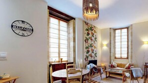 A cozy living room with a round table, chairs, a sofa, and a clock on the wall.