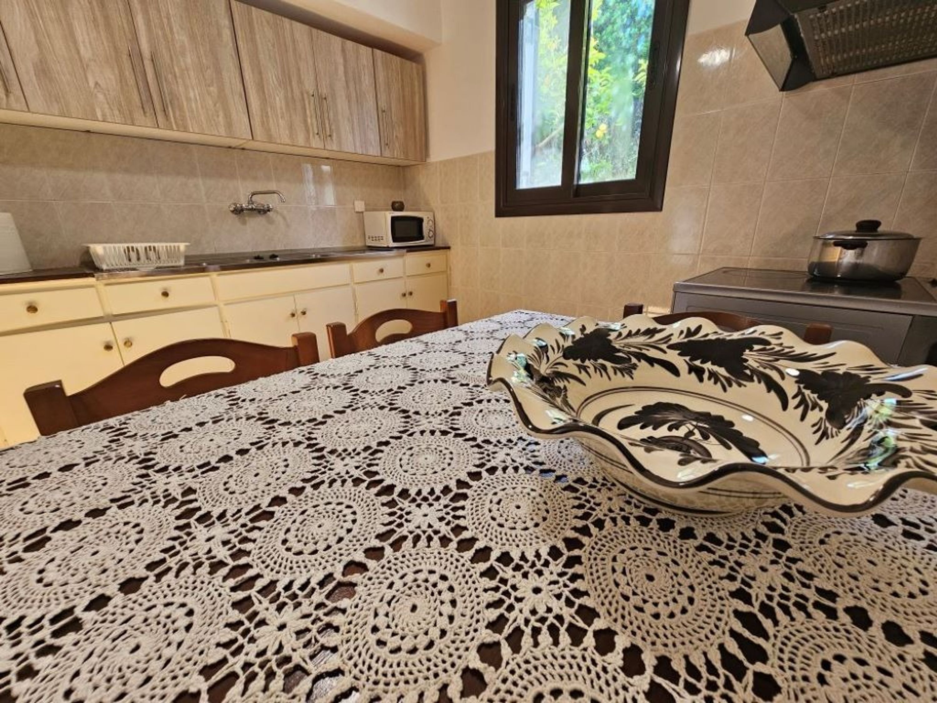 Una cucina con mobili in legno, un forno a microonde e una finestra vista verde.