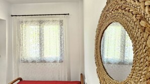 Una stanza con un letto, uno specchio grande e una finestra con tende leggere.
