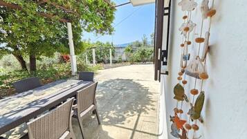 An outdoor patio with a table and chairs, a pergola, and a decorative wall.