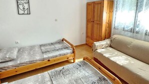 Una stanza con due letti in legno, un armadio in legno, un divano beige e un condizionatore d'aria a parete.