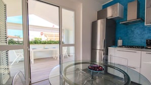 Una cocina moderna con una mesa de comedor de vidrio, electrodomésticos de acero inoxidable y vistas al exterior.