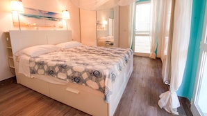 Un dormitorio con cama, lámparas de noche, un espejo y una ventana con cortinas.