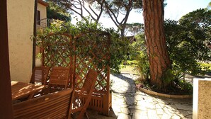 A patio area with wooden furniture and a stone pathway. - Appartamento Puccini (Grosseto)