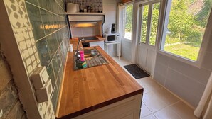 Een moderne keuken met een houten aanrecht, een spoelbak, een magnetron en een raam met uitzicht op groen.