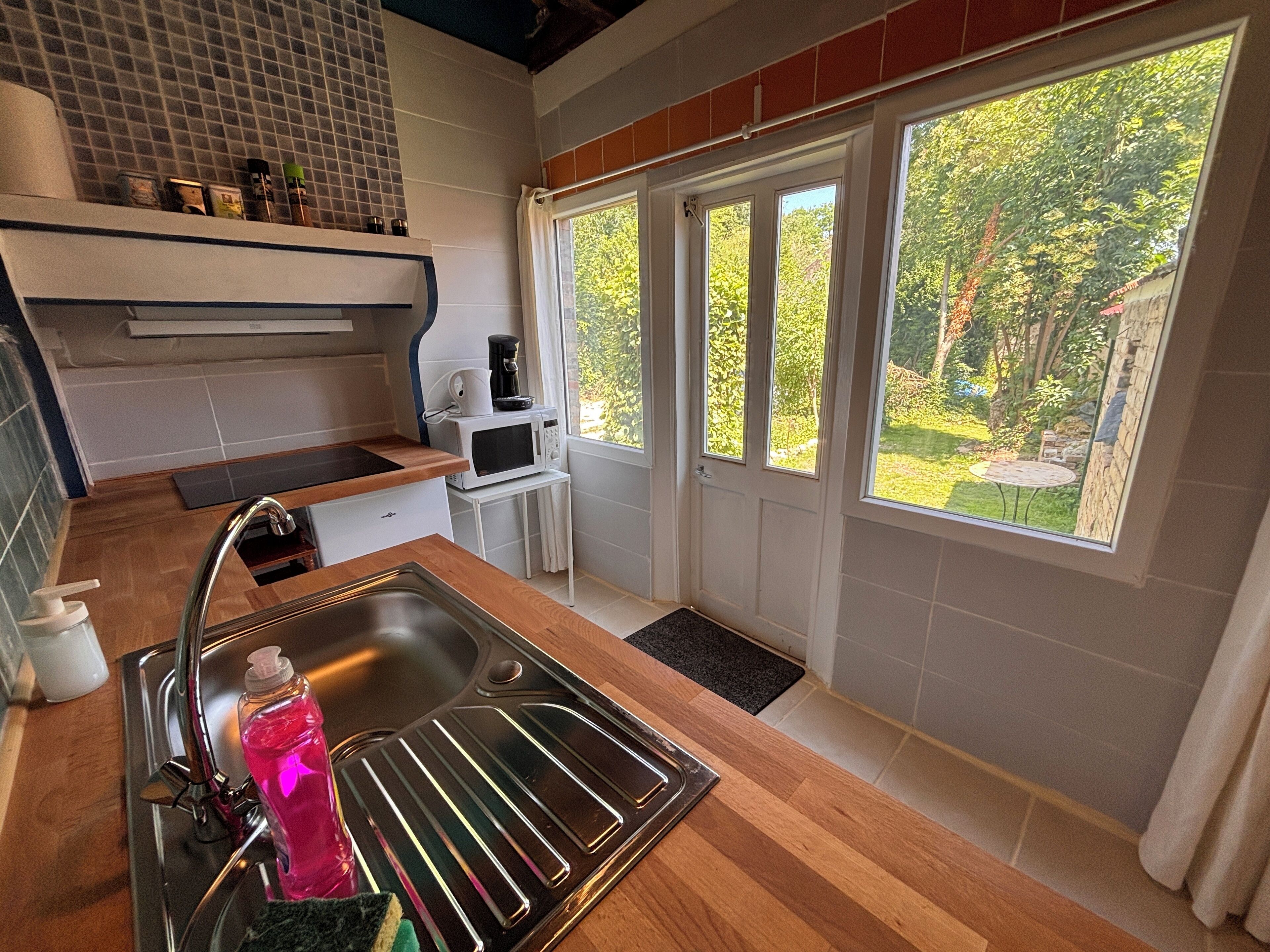 A compact kitchen with a sink, a microwave, and a coffee maker on a small table.