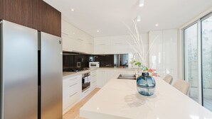 A modern kitchen with a central island, stainless steel appliances, and a large window providing natural light.