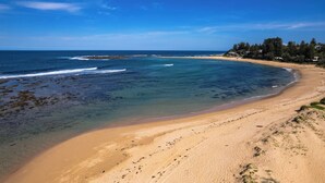 Una playa con agua cristalina, orilla de arena y un área boscosa al fondo.