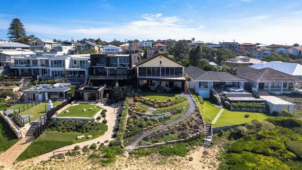 Una zona residencial moderna con una casa destacada que tiene un patio delantero grande, una entrada para vehículos y un jardín cuidado.
