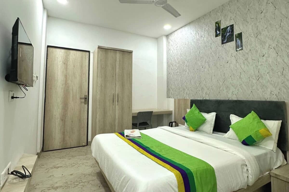 A bedroom with a bed, a desk, a chair, a wardrobe, a ceiling fan, and a TV.