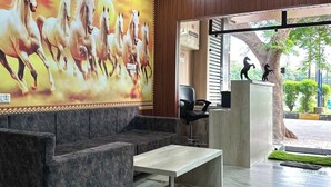 Un hall d’entrée orné d’une grande fresque représentant des chevaux, doté d’un ventilateur de plafond, d’un comptoir de réception et d’un espace salon avec une table basse.