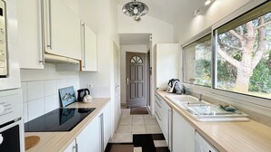 A modern kitchen with white cabinets, a black countertop, and a window with a view of trees. - Prestigious golf and ocean villa rental (Moliets-et-Maa)