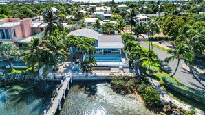 A coastal property with a swimming pool, palm trees, and a dock. - Sunset Key Escape Waterfront Pool Home with Dock and Sunset Views (Marathon)