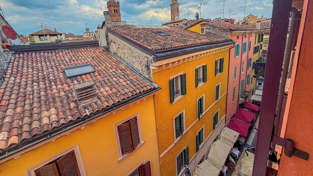 A view of a narrow street with terracotta-tiled roofs and colorful buildings. - [Piazza Erbe] Residence Skyline View 360 [Free Parking] (Verona)