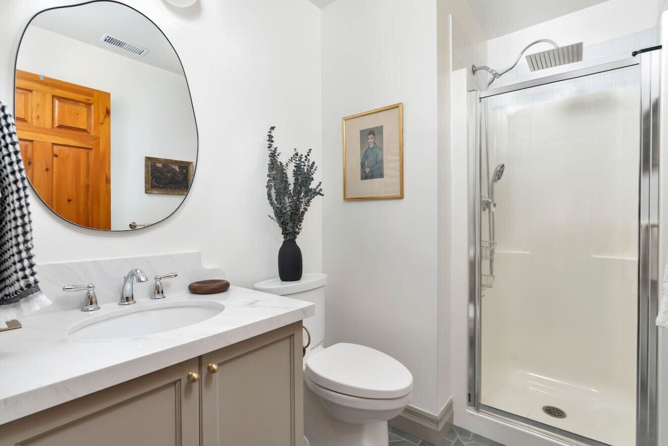 Une salle de bain avec un lavabo blanc, des toilettes, une douche et un miroir.