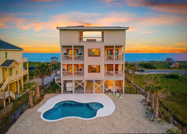 A multi-story beachfront property with a pool, balconies, and a view of the ocean.
