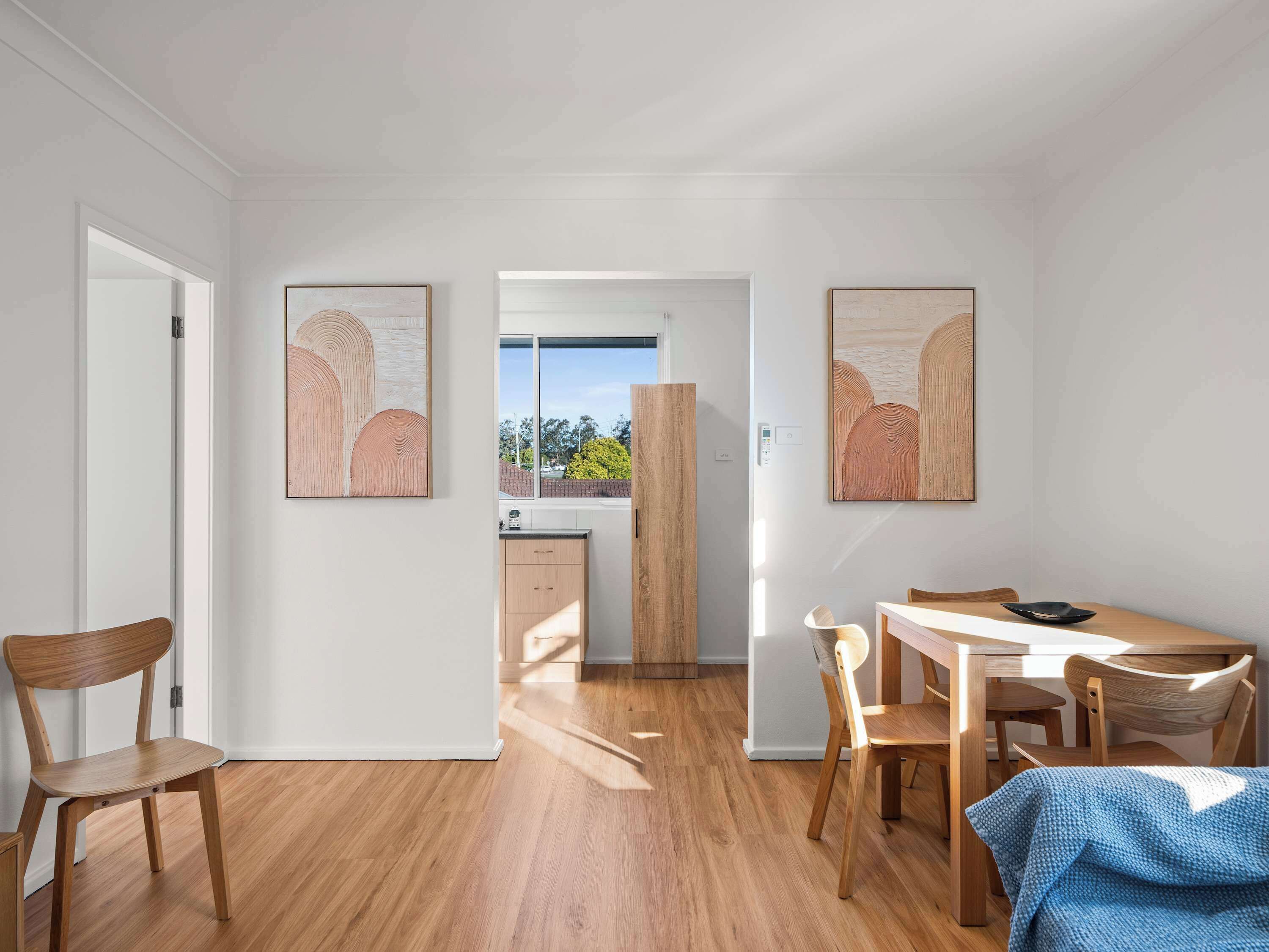 A modern interior with a dining area, wooden furniture, and artwork on the walls.
