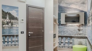 A modern bathroom with a wooden door, a mounted TV, and a decorative fountain. - Hotiday Como Paoli (Como)