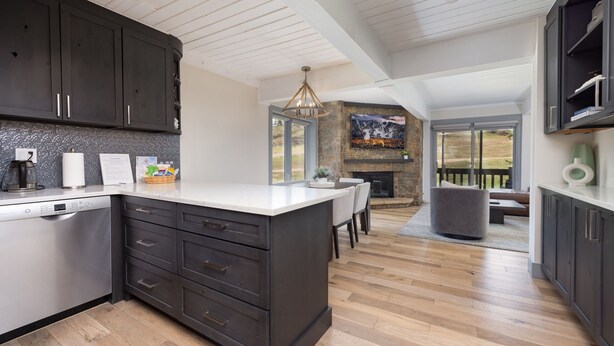 A modern kitchen with dark cabinets, a white countertop, and a built-in dishwasher.