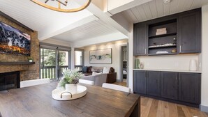 A modern kitchen with dark cabinets, a wooden dining table, and a fireplace.