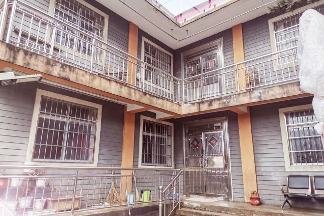 Un edificio de varios pisos con ventanas protegidas por barrotes, balcones, una entrada central y una escalera que sube a los pisos superiores.