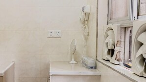A bathroom with a white countertop, a hairdryer, a mirror, and two wall-mounted fans.