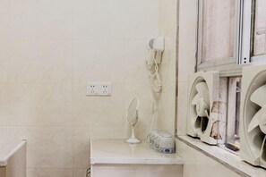 Een badkamer met een wit aanrecht, een haardroger, een spiegel en twee wandventilatoren.