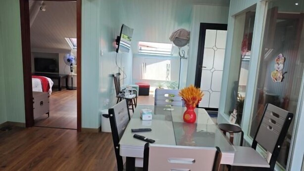 A dining area with a glass table, chairs, and a vase with flowers.