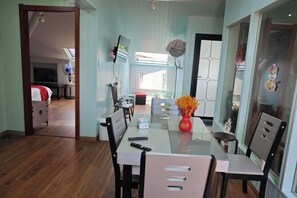 Un comedor con una mesa de vidrio, sillas y un jarrón con flores.
