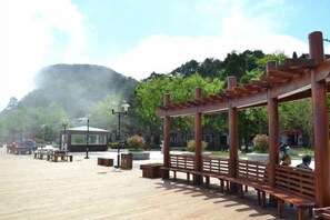 A wooden deck with benches and a gazebo, surrounded by greenery and a mountain backdrop. - Lushan Jinju Apartment (Lushan Cableway Upper Station) (Lushan City)