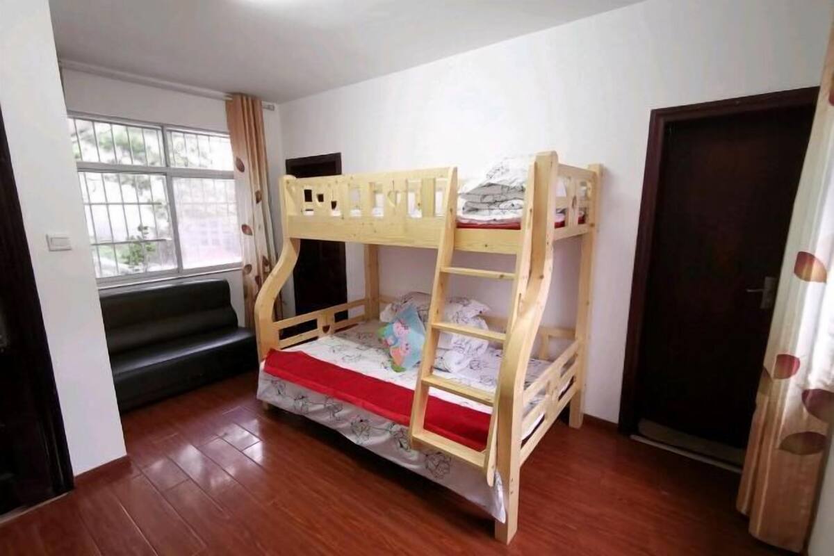 Une chambre avec un lit superposé, une fenêtre, une porte et un escalier.