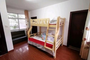 Une chambre avec un lit superposé, une fenêtre, une porte et un escalier.