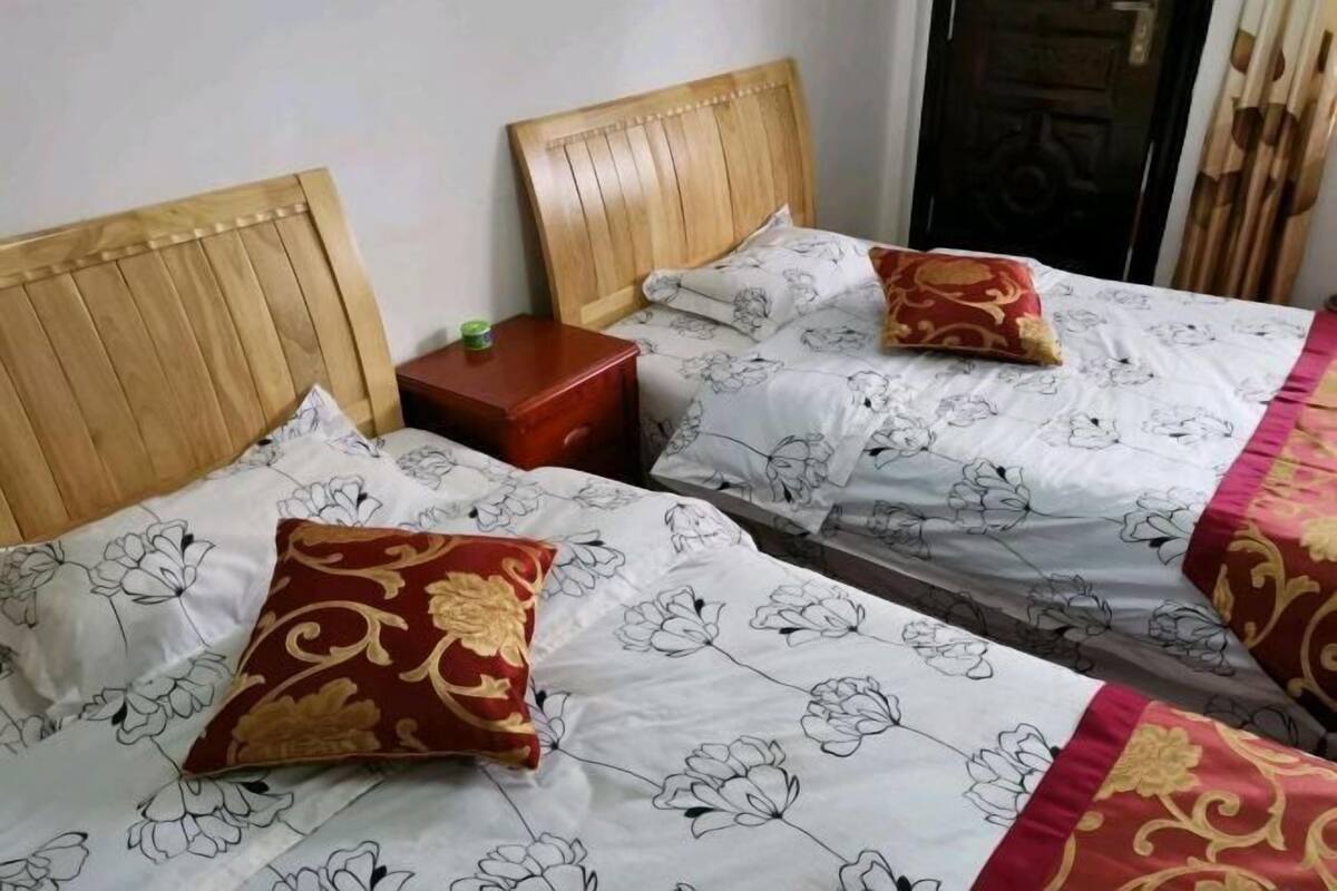 Deux lits avec des têtes de lit en bois, une table de chevet et une porte au design traditionnel.