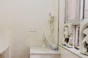 Un baño con espejo, secador de pelo y dos ventiladores de pared.