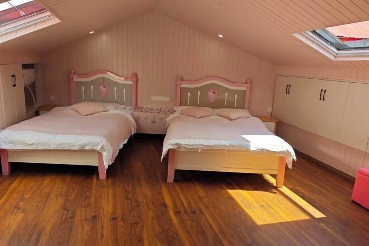 Une chambre avec deux lits, un plancher en bois et un plafond en pente doté de fenêtres de toit.