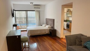 Een hotelkamer met een bed, een bureau, een stoel, een bank en een kitchenette.